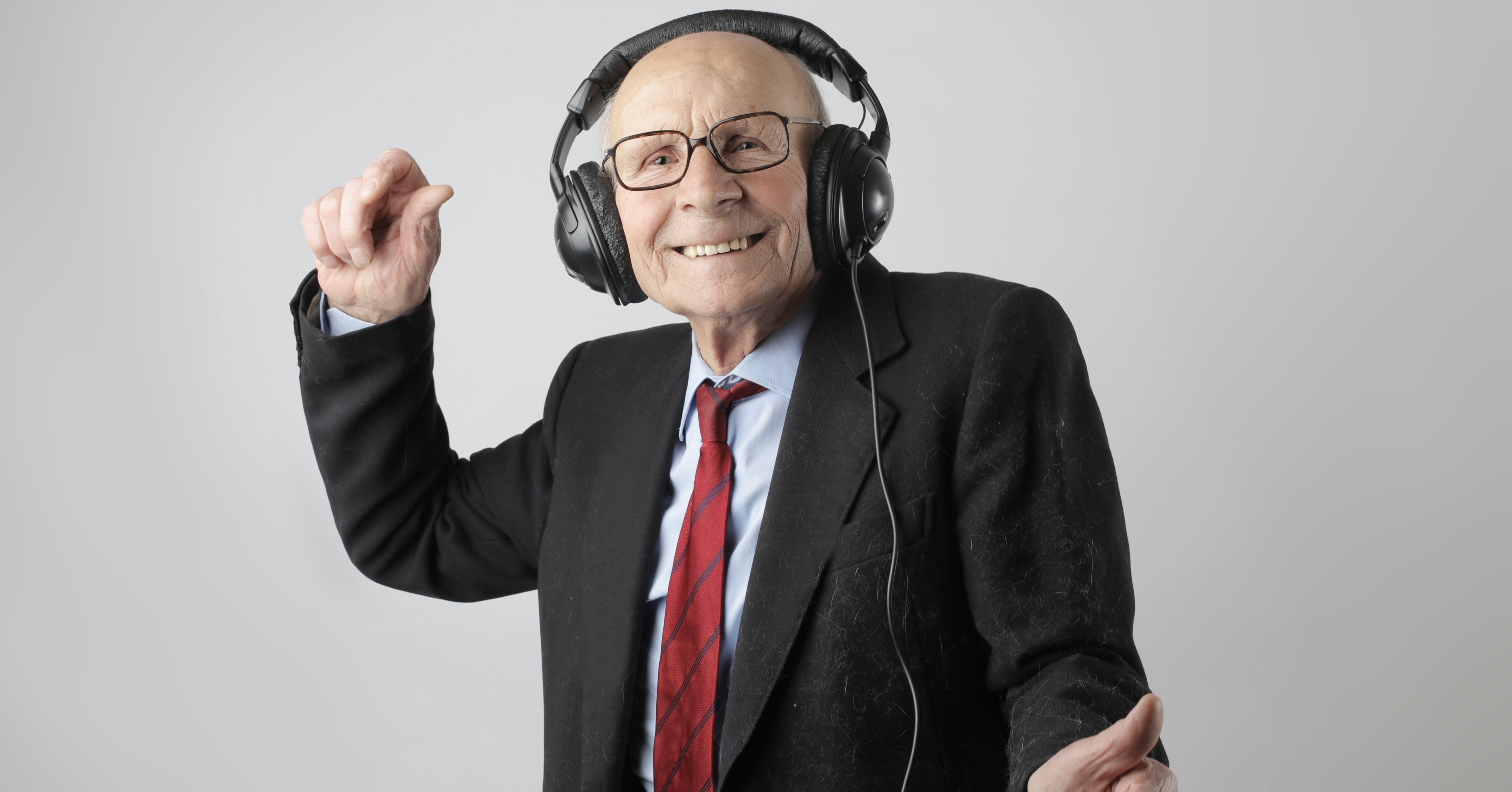 Cheerful elderly man listening to music in headphones